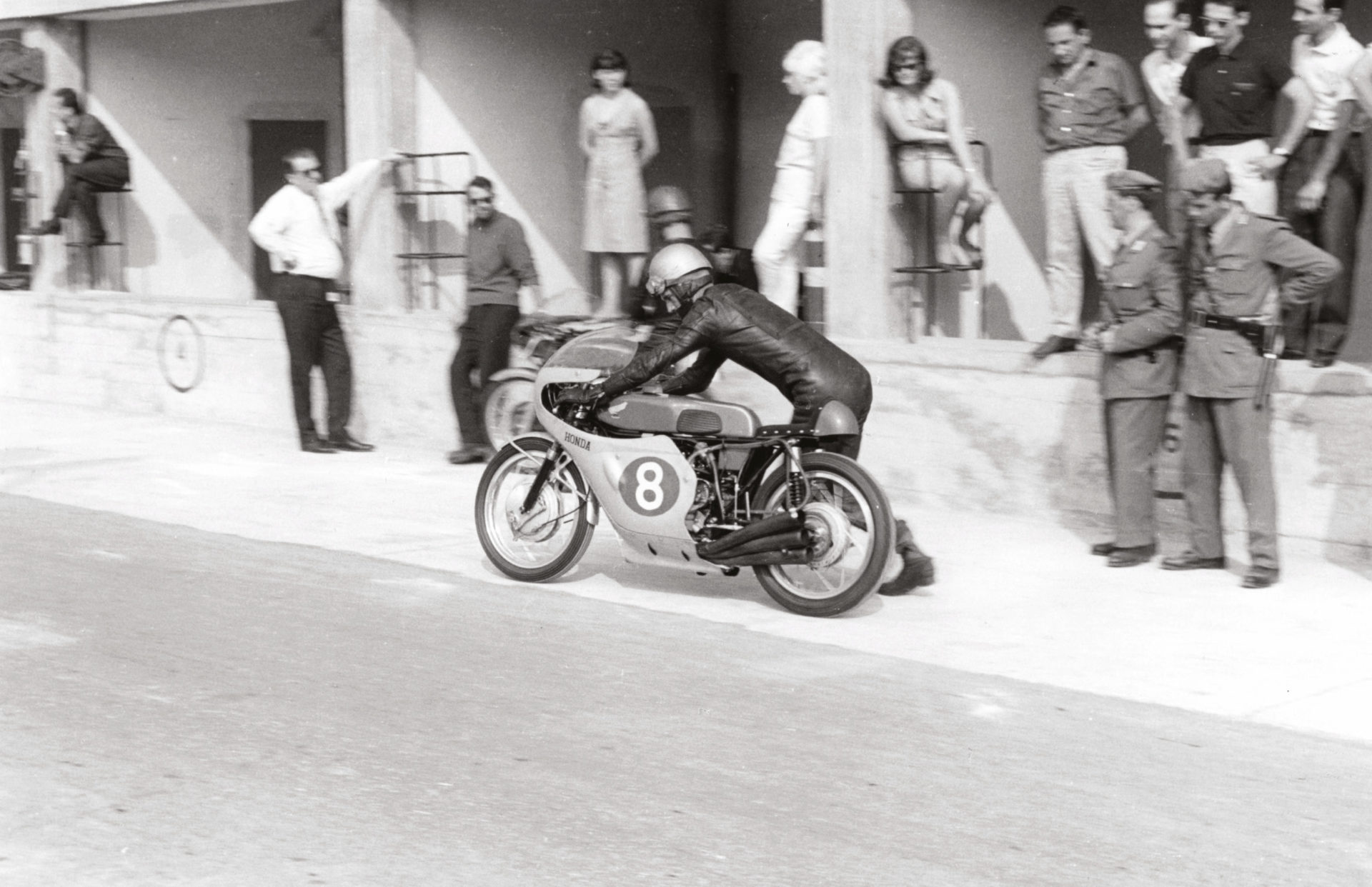 Jim Redman bumps Honda’s brand-new 250 six into life at Monza, September 1964. The bike “sounded like the end of the world” – it was so loud that Dunlop technicians refused to check its rear tyre when the engine was running