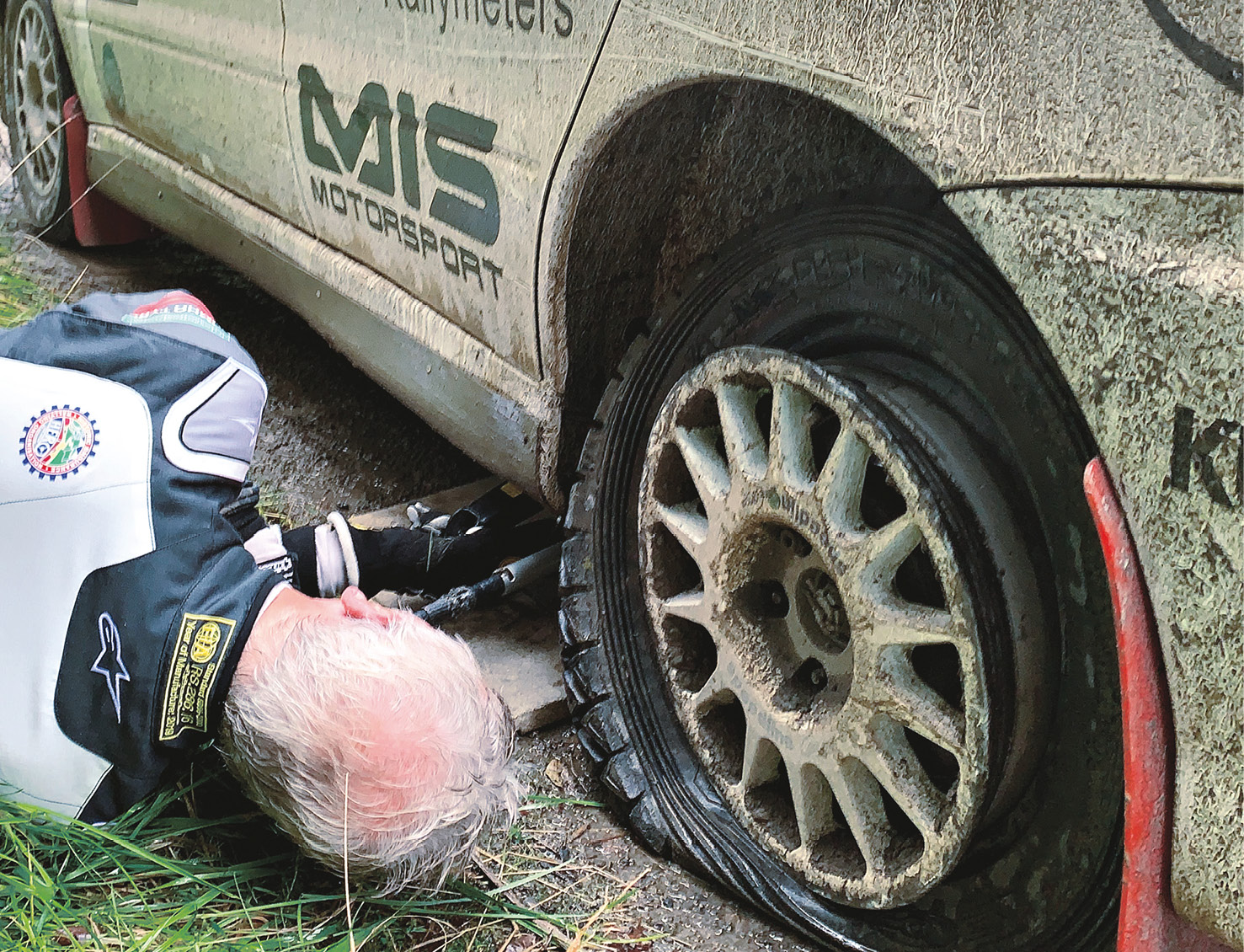 The moment you realise that white overalls weren’t a good idea. Jardine gets down to the dirty work to jack up the Evo and replace a rear puncture that cost time