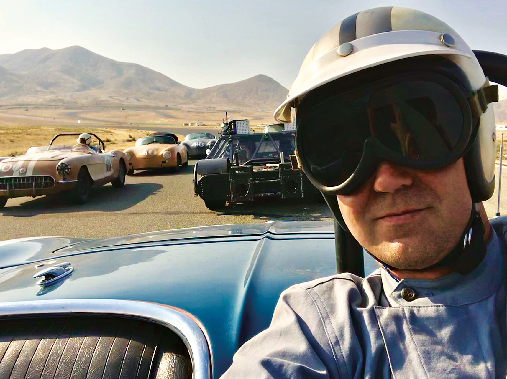 Hill on board a Corvette ready to recreate a race at Willow Springs Raceway, with filming vehicle behind.